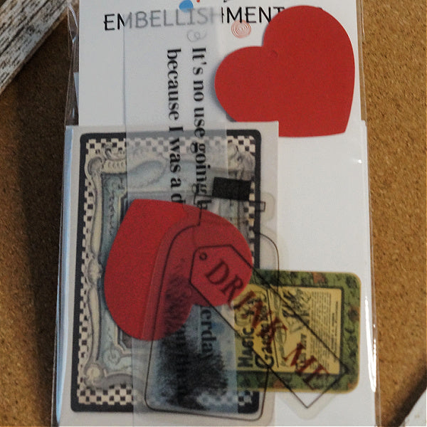 Front view of packaged Alice in Wonderland Mini Kit with Embellishmentals label, red heart tags, vellum quote, and printed card designs.