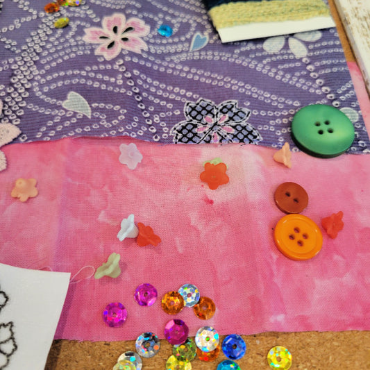 Colorful buttons and sequins on a pink hand dyed fabric background with vintage kimono silk
